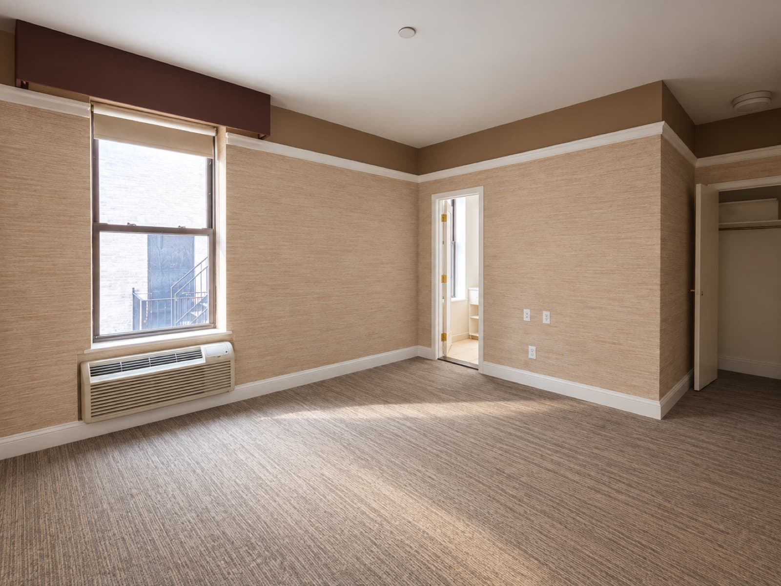 The empty room, window side with the closet and a doorway at The 46, 129 West 46th Street, Midtown NYC