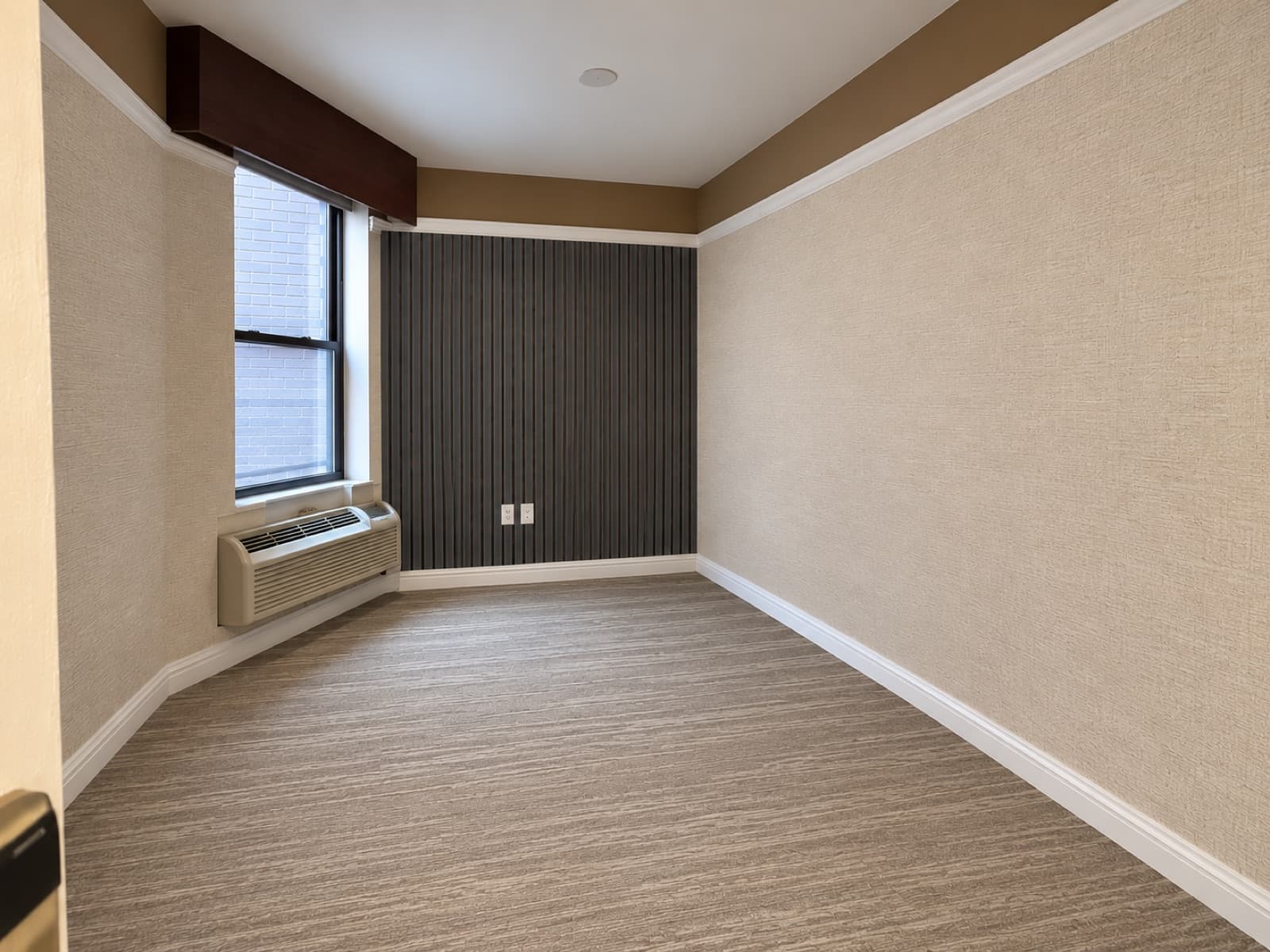 The empty room, window side with the slatted accent wall at The 46, 129 West 46th Street, Midtown NYC