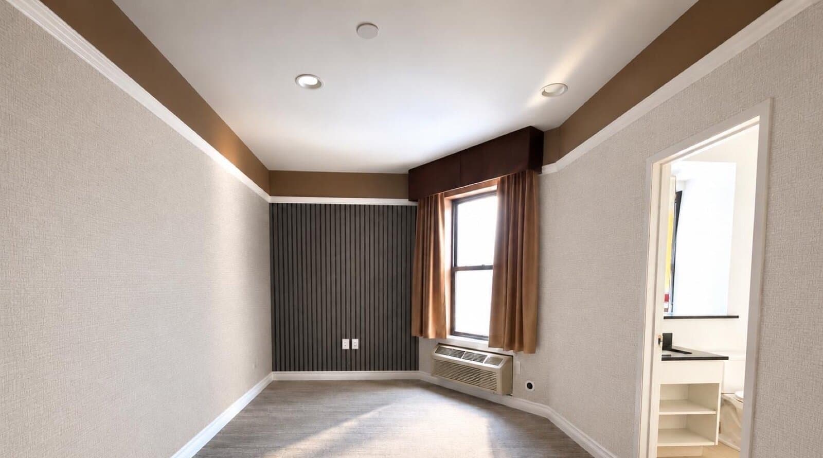 The empty room, facing the window and slatted accent wall at The 46, 129 West 46th Street, Midtown NYC